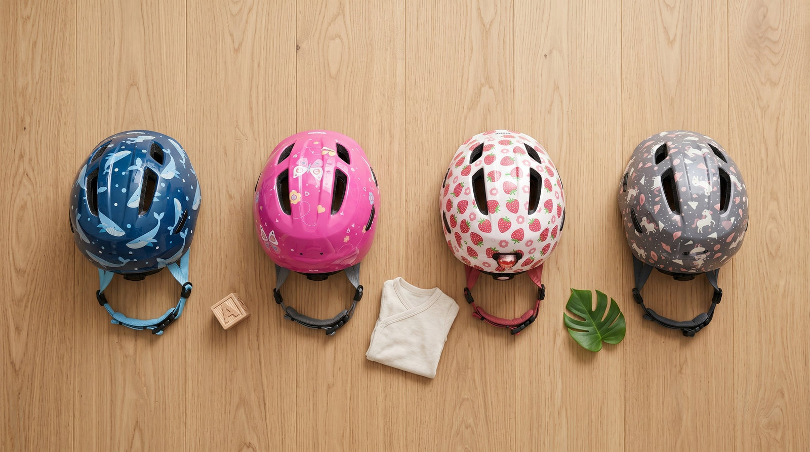 7 baby cykelhjelme i flatlay — Abus Smiley 3.0 i blå, pink og rose, samt grå